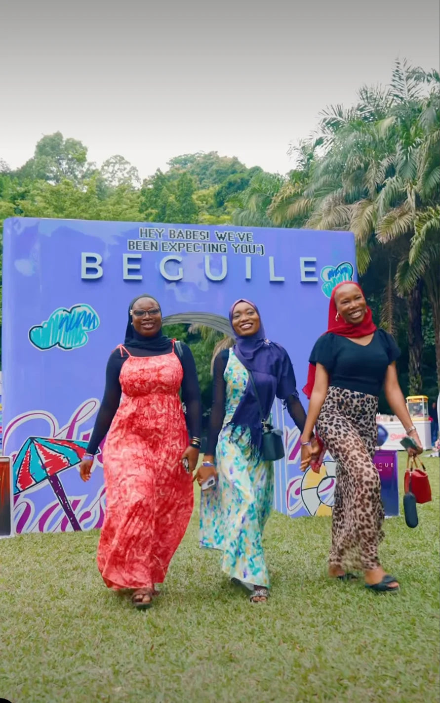 Three women walking past the Beguile wall at Summer Has a Scent in Abuja